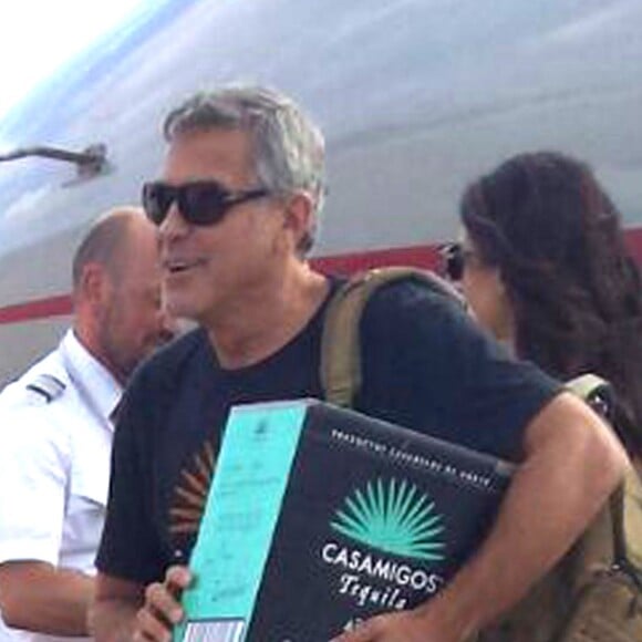 Exclusif - George Clooney et sa femme Amal Alamuddin Clooney débarquent d'un jet à Ibiza en compagnie de Cindy Crawford et son mari Rande Gerber le 22 août 2015. Il descend de l'avion avec un carton de sa Tequila "Casamigos" sous le bras.