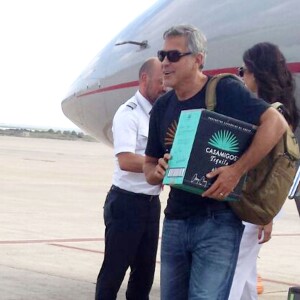 Exclusif - George Clooney et sa femme Amal Alamuddin Clooney débarquent d'un jet à Ibiza en compagnie de Cindy Crawford et son mari Rande Gerber le 22 août 2015. Il descend de l'avion avec un carton de sa Tequila "Casamigos" sous le bras.