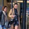 Chrissy Teigen, enceinte, quitte le centre commercial Barneys New York avec sa mère Vilailuck Teigen à Beverly Hills, habillée d'un manteau beige, d'une robe à motifs floraux Alexander McQueen et de bottines Isabel Marant. Des lunettes de soleil Victoria Beckham et un sac à franges Chloé (modèle Hudson, collection hiver 2015) accessoirisent la tenue de la future maman. Le 24 novembre 2015.