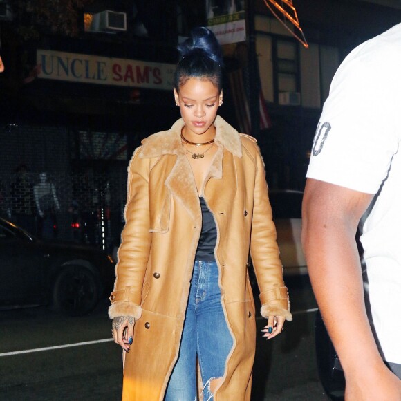 Rihanna de sortie à New York, porte un manteau camel en cuir Chanel, un top noir en satin, un jean Citizens of Humanity et des bottines en dentelle Christian Dior. Le 21 novembre 2015.