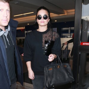 Demi Lovato signe la guitare d'un fan à son arrivée à l'aéroport LAX de Los Angeles le 22 janvier 2016.