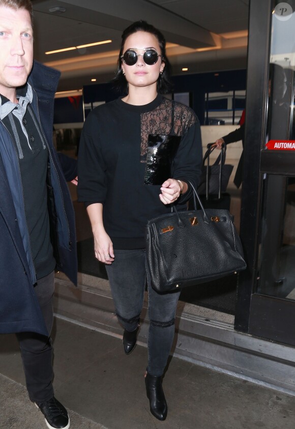 Demi Lovato signe la guitare d'un fan à son arrivée à l'aéroport LAX de Los Angeles le 22 janvier 2016.