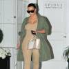 Kim Kardashian à la sortie du centre dermatologique Epione à Beverly Hills, porte une parka kaki, un body beige, et des sandales transparentes Prada (collection printemps-été 2010). Des lunettes de soleil Saint Laurent et un sac Hermès complètent sa tenue. Le 2 mars 2016.