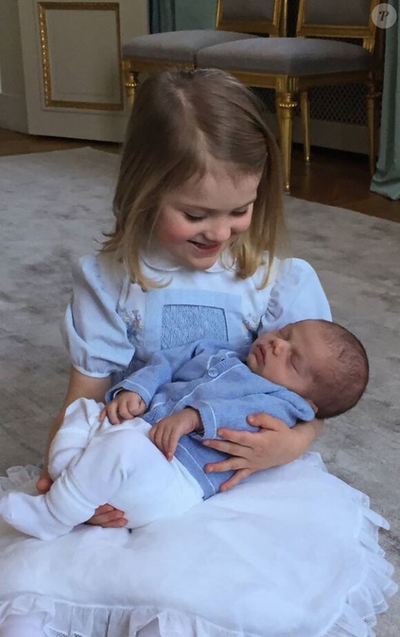 La princesse Estelle de Suède tenant son petit frère le prince Oscar, photographiés en mars 2016 par leur papa le prince Daniel.