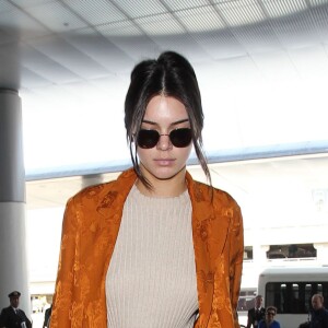 Kendall Jenner à l'aéroport LAX à Los Angeles, porte un blazer en satin Etro, un top et un pantalon Elle Sasson et des baskets Kenneth Cole. Des lunettes de soleil The Row et un sac Givenchy (Lucrezia) accessoirisent sa tenue. Le 10 mai 2016.