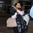 Ariana Grande se cache des photographes à son arrivée à l'aéroport de LAX à Los Angeles, le 3 juillet 2015
