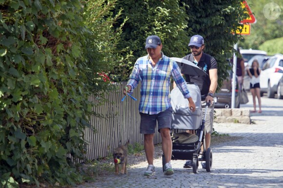 Le prince Carl Philip de Suède promène son fils le prince Alexander pendant que la princesse Sofia assiste à un séminaire à Bastad, la ville où ils se sont connus, le 4 août 2016. Il est accompagné d'un garde du corps qui promène le chien de la famille, Siri.