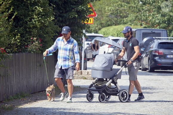 Le prince Carl Philip de Suède promène son fils le prince Alexander pendant que la princesse Sofia assiste à un séminaire à Bastad, la ville où ils se sont connus, le 4 août 2016. Il est accompagné d'un garde du corps qui promène le chien de la famille, Siri.
