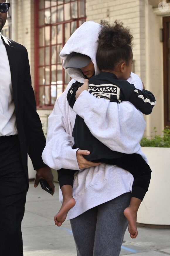 Kim Kardashian, cachée par ses vêtements, et sa fille North sortent de son appartement à New York, le 6 octobre 2016.