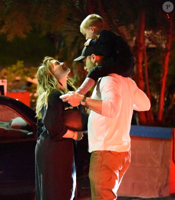 Exclusif - Hilary Duff embrasse son compagnon Jason Walsh (qui porte son fils Luca sur ses épaules!) à la sortie d'un marché à Los Angeles, le 31 octobre 2016. 
