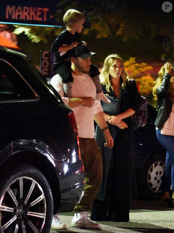 Exclusif - Hilary Duff embrasse son compagnon Jason Walsh (qui porte son fils Luca sur ses épaules!) à la sortie d'un marché à Los Angeles, le 31 octobre 2016. 