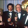 John Barry, oscarisé pour la musique d'Out of Africa, entouré de Debbie Reynolds et Lionel Richie lors des Oscars 1986.