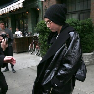 Cara Delevingne, cachée sous un bonnet et un énorme manteau noir, sort d'un immeuble à New York, le 30 avril 2017.