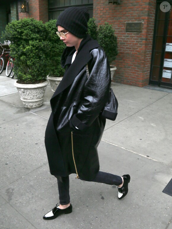 Cara Delevingne, cachée sous un bonnet et un énorme manteau noir, sort d'un immeuble à New York, le 30 avril 2017.