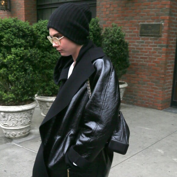 Cara Delevingne, cachée sous un bonnet et un énorme manteau noir, sort d'un immeuble à New York, le 30 avril 2017.