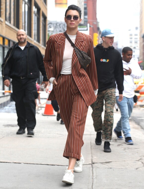 Kendall Jenner photographiée à New York le 5 juin 2017, porte une veste et un pantalon rayés Wolk Morais ("Collection 5", automne-hiver 2017), une banane Louis Vuitton et des baskets YEEZY (modèle adidas Powerphase "Calabasas").