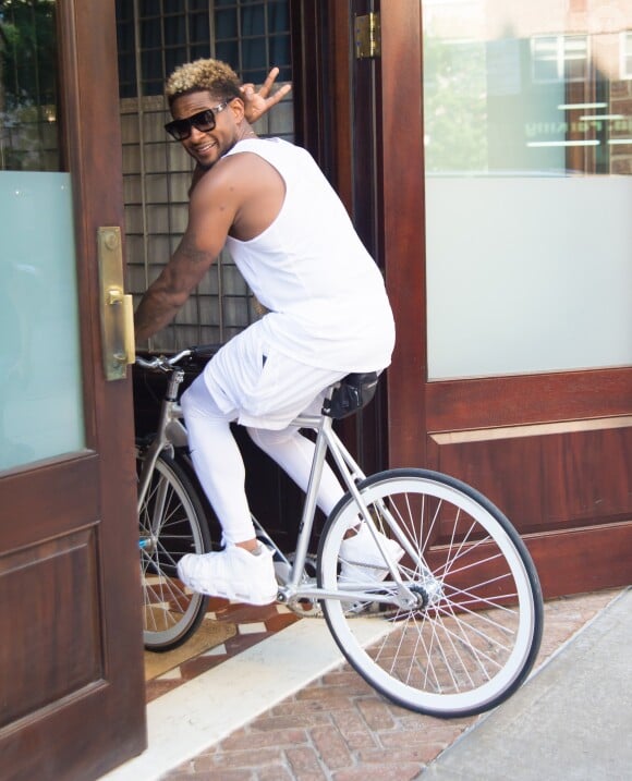 Usher rentre en souriant avec un vélo dans le hall de son hôtel à New York, le 12 juin 2017