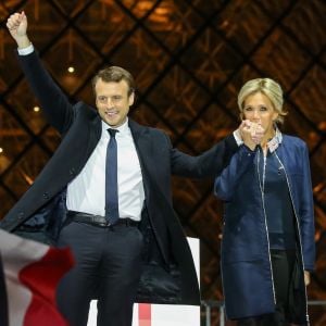 Emmanuel Macron, élu président de la république, et sa femme Brigitte Macron, saluent les militants devant la pyramide au musée du Louvre à Paris, après sa victoire lors du deuxième tour de l'élection présidentielle. Le 7 mai 2017.