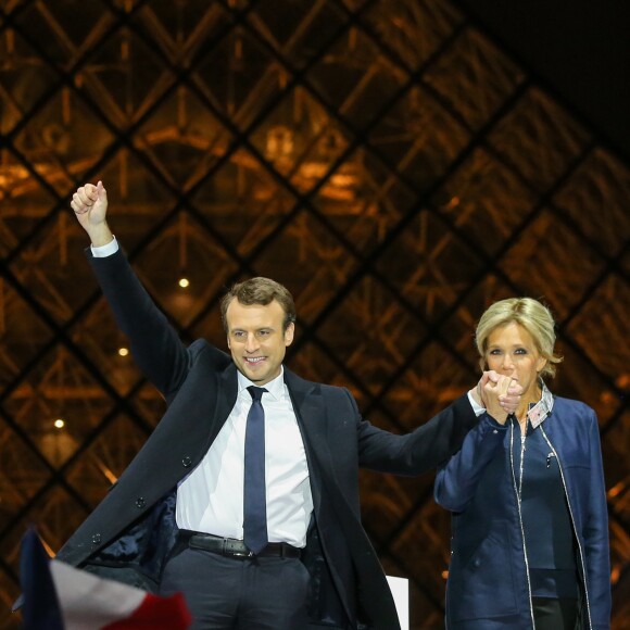 Emmanuel Macron, élu président de la république, et sa femme Brigitte Macron, saluent les militants devant la pyramide au musée du Louvre à Paris, après sa victoire lors du deuxième tour de l'élection présidentielle. Le 7 mai 2017.