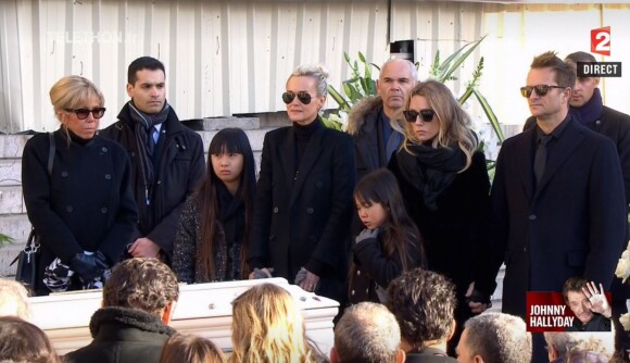 Brigitte Macron et les proches du rockeur devant la dépouille lors des obsèques de la star à l'église de la Madeleine à Paris, le 9 décembre 2017.
