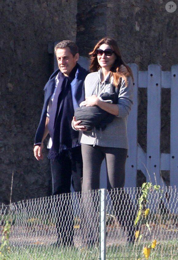 NICOLAS SARKOZY, EN PAPA ATTENTIONNE, SE BALADE AVEC SA FEMME CARLA BRUNI-SAKOZY, QUI AFFICHE DEJA UNE BELLE LIGNE, ET LEUR PETITE GIULIA, A LA LANTERNE, DANS LE PARC DU CHATEAU DE VERSAILLES. LE PRESIDENT ENLACE TENDREMENT SON EPOUSE QUI TIENT LE BEBE. 2011.31/10/2011 - VERSAILLES