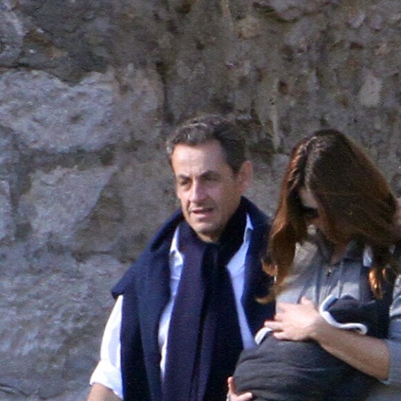 NICOLAS SARKOZY, EN PAPA ATTENTIONNE, SE BALADE AVEC SA FEMME CARLA BRUNI-SAKOZY, QUI AFFICHE DEJA UNE BELLE LIGNE, ET LEUR PETITE GIULIA, A LA LANTERNE, DANS LE PARC DU CHATEAU DE VERSAILLES. LE PRESIDENT ENLACE TENDREMENT SON EPOUSE QUI TIENT LE BEBE. .31/10/2011 - VERSAILLES
