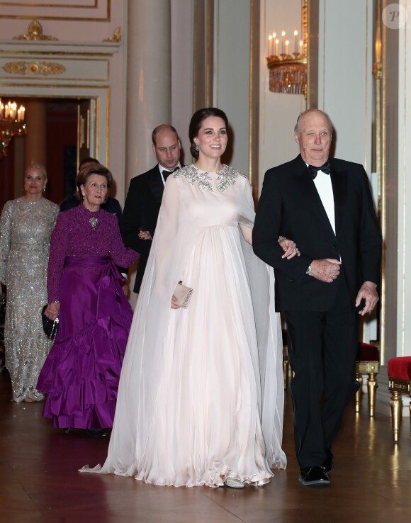 La duchesse Catherine de Cambridge, enceinte et en Alexander McQueen, arrive au bras du roi Harald V de Norvège au palais royal à Oslo le 1er février 2018 pour le dîner organisé dans le cadre de sa visite officielle avec le prince William, qui suit en donnant le bras à la reine Sonja.