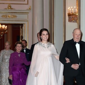 La duchesse Catherine de Cambridge, enceinte et en Alexander McQueen, arrive au bras du roi Harald V de Norvège au palais royal à Oslo le 1er février 2018 pour le dîner organisé dans le cadre de sa visite officielle avec le prince William.