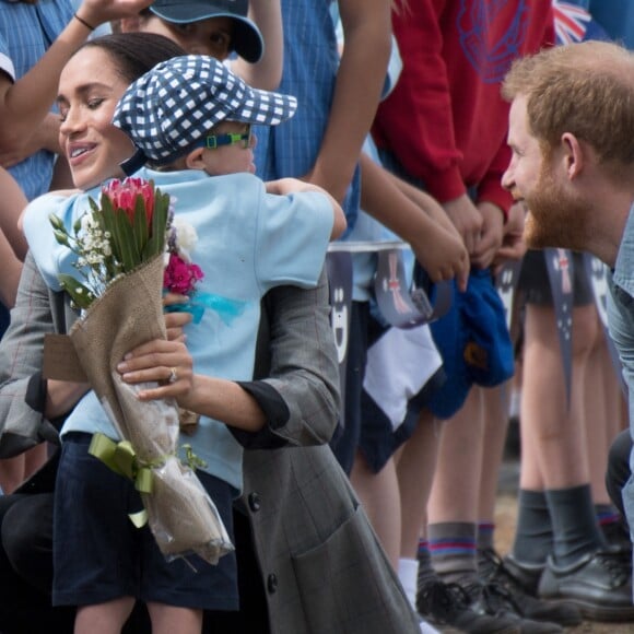 Le prince Harry et Meghan Markle accueillis par des élèves australiens, ont vécu un adorable moment lorsqu'un petit garçon de 5 ans, atteint de trisomie 21, a sauté dans les bras du prince avant de faire un câlin à la duchesse à leur arrivée à Dubbo, le 17 octobre 2018.