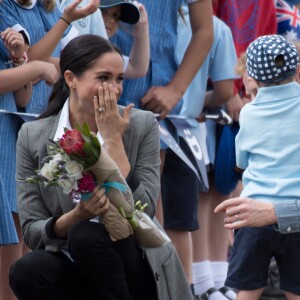 Le prince Harry et Meghan Markle accueillis par des élèves australiens, ont vécu un adorable moment lorsqu'un petit garçon de 5 ans, atteint de trisomie 21, a sauté dans les bras du prince avant de faire un câlin à la duchesse à leur arrivée à Dubbo, le 17 octobre 2018.