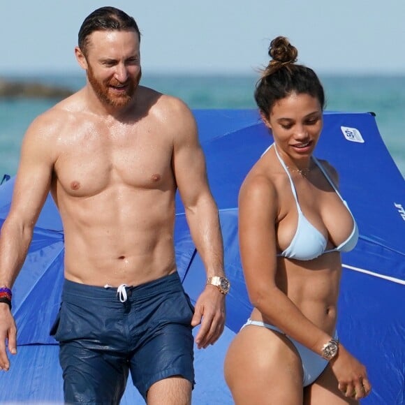 David Guetta et sa compagne Jessica Ledon profitent d'une belle journée ensoleillée en compagnie de leur petit Bulldog sur une plage à Miami le 19 novembre 2018