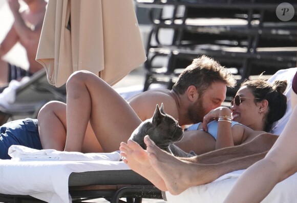 David Guetta et sa compagne Jessica Ledon profitent d'une belle journée ensoleillée en compagnie de leur petit Bulldog sur une plage à Miami le 19 novembre 2018