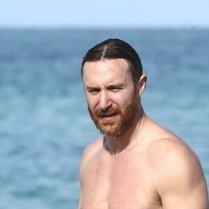 David Guetta et sa compagne Jessica Ledon profitent d'une belle journée ensoleillée en compagnie de leur petit Bulldog sur une plage à Miami le 19 novembre 2018