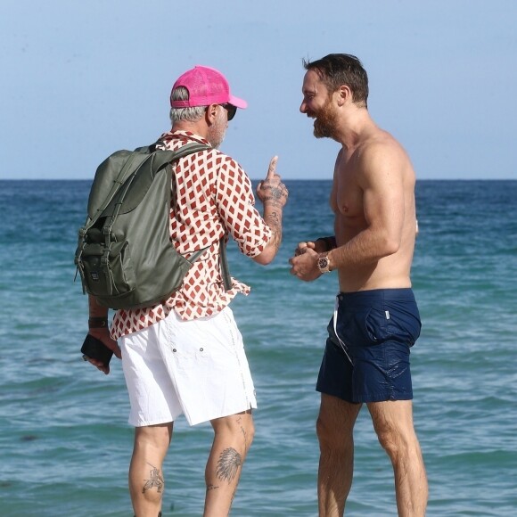 David Guetta et sa compagne Jessica Ledon profitent d'une belle journée ensoleillée en compagnie de leur petit Bulldog sur une plage à Miami. David Guetta retrouve son ami Gianluca Vacchi sur la plage. Le 19 novembre 2018