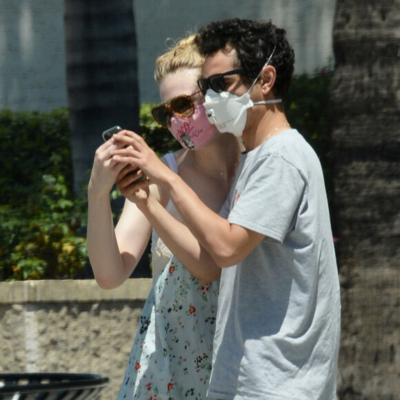 Exclusif - Elle Fanning et son compagnon Max Minghella font des selfies avec leurs masques lors d'une balade à Los Angeles, le 12 mai 2020.