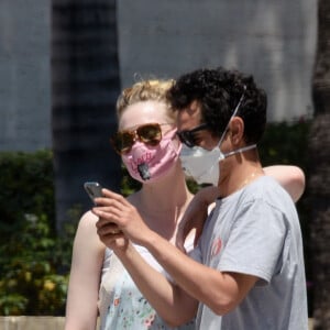 Exclusif - Elle Fanning et son compagnon Max Minghella font des selfies avec leurs masques lors d'une balade à Los Angeles, le 12 mai 2020.