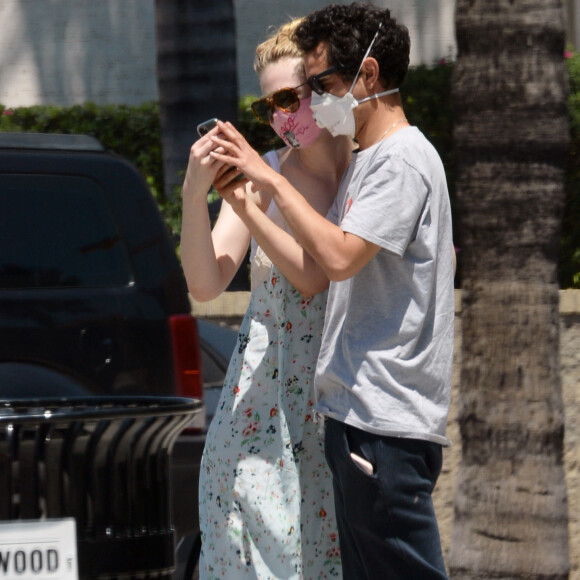Exclusif - Elle Fanning et son compagnon Max Minghella font des selfies avec leurs masques lors d'une balade à Los Angeles, le 12 mai 2020.