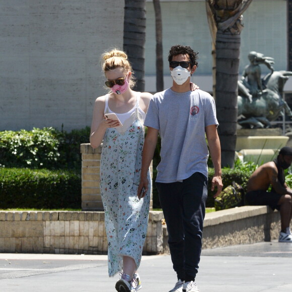 Exclusif - Elle Fanning et son compagnon Max Minghella font des selfies avec leurs masques lors d'une balade à Los Angeles, le 12 mai 2020.