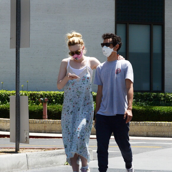 Exclusif - Elle Fanning et son compagnon Max Minghella font des selfies avec leurs masques lors d'une balade à Los Angeles, le 12 mai 2020.