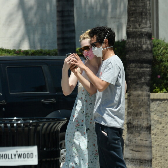 Exclusif - Elle Fanning et son compagnon Max Minghella font des selfies avec leurs masques lors d'une balade à Los Angeles, le 12 mai 2020.