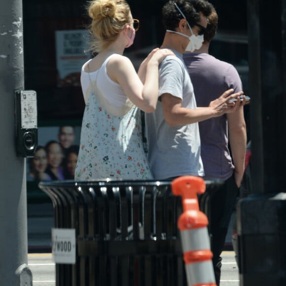 Exclusif - Elle Fanning et son compagnon Max Minghella font des selfies avec leurs masques lors d'une balade à Los Angeles, le 12 mai 2020.