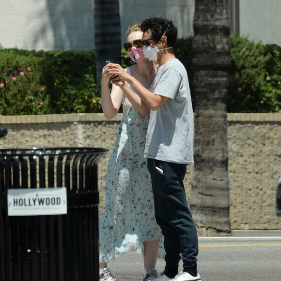 Exclusif - Elle Fanning et son compagnon Max Minghella font des selfies avec leurs masques lors d'une balade à Los Angeles, le 12 mai 2020.