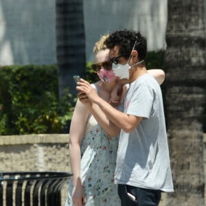 Exclusif - Elle Fanning et son compagnon Max Minghella font des selfies avec leurs masques lors d'une balade à Los Angeles, le 12 mai 2020.