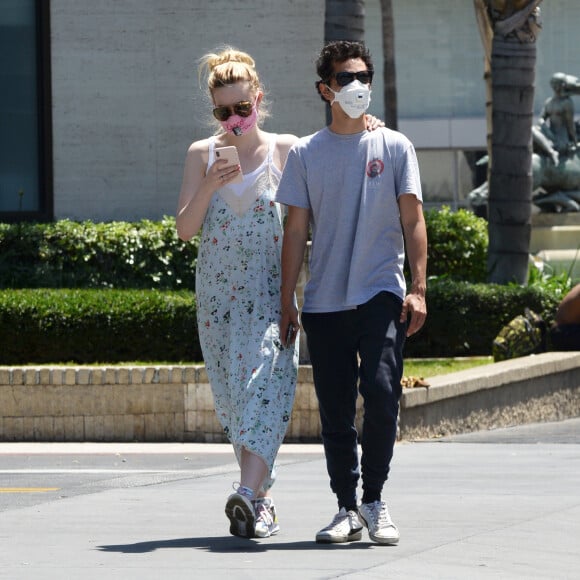 Exclusif - Elle Fanning et son compagnon Max Minghella font des selfies avec leurs masques lors d'une balade à Los Angeles, le 12 mai 2020.