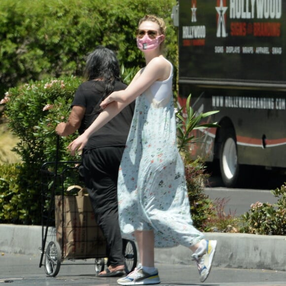 Exclusif - Elle Fanning et son compagnon Max Minghella font des selfies avec leurs masques lors d'une balade à Los Angeles, le 12 mai 2020.