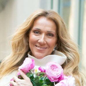 Celine Dion rayonnante et très souriante dans un ensemble pull écru et jupe bouffante fleurie salue ses fans à la sortie de son hôtel à New York, le 8 mars 2020 