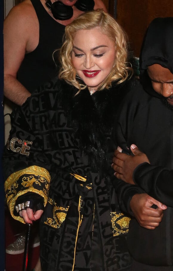 Madonna porte un manteau Versace et marche à l'aide d'une canne à la sortie du London Palladium à Londres.