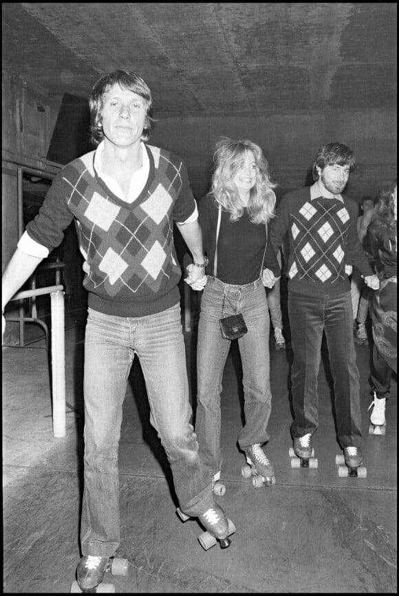 Archives - Yves Rénier, Goldie Hawn et Steven Spielberg sur des patins à roulettes lors d'une soirée à la main jaune.