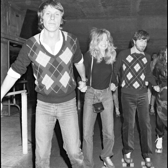 Archives - Yves Rénier, Goldie Hawn et Steven Spielberg sur des patins à roulettes lors d'une soirée à la main jaune.