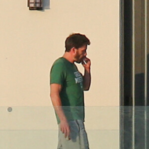 Ben Affleck fume une cigarette sur le balcon de la maison qu'il loue avec Jennifer Lopez à Miami le 25 mai 2021. 
